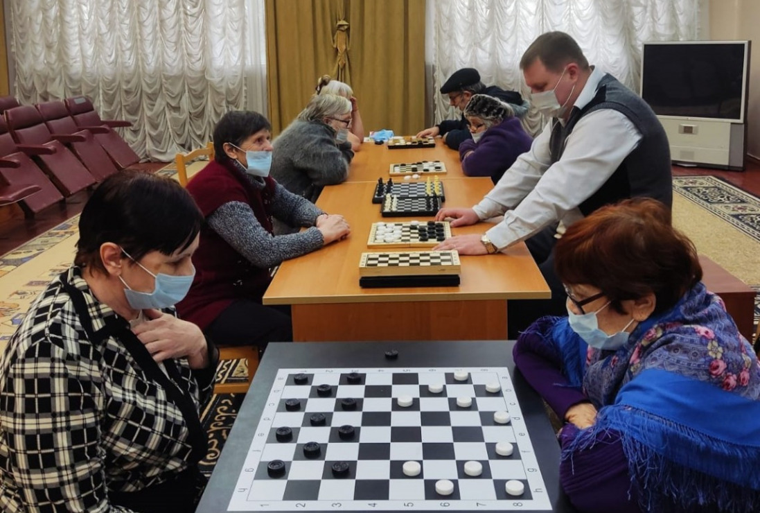 Проведение турнира по игре в шашки. За столами собрались участники турнира - любители шашек.